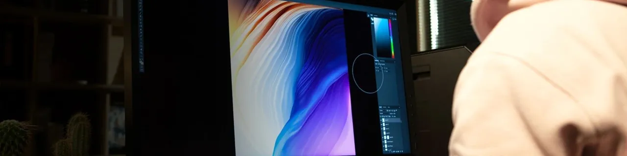 Person viewing abstract digital art featuring blue and orange waves on a computer monitor.